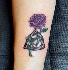 a rose tattoo on the arm with celtic symbols and a knot around it, as well as a flower