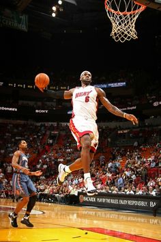 a basketball player jumping up to dunk the ball in front of an audience at a game