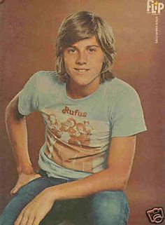 an old photo of a young man sitting on a stool with his hands on his hips