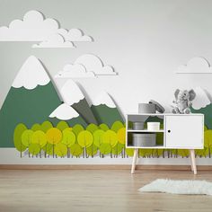 an empty room with a white dresser and green trees painted on the wall