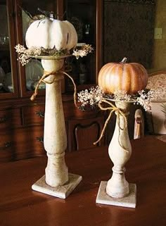 two white pumpkins sitting on top of pedestals in the middle of a dining room