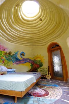 a bed sitting under a round window next to a wall with paintings on the walls