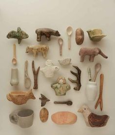 several different types of clay animals and spoons on a white surface with a cup in the middle