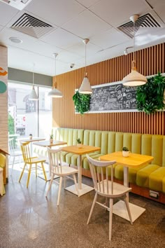 the interior of a restaurant with yellow and green booths, wooden tables, and chairs