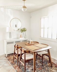 a dining room table with chairs and a rug on the floor in front of it