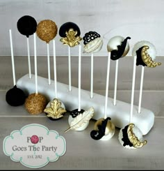 there are many cake pops on the stick and one is black, white and gold