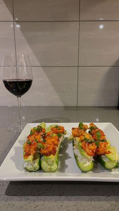 a white plate topped with cucumbers next to a glass of wine