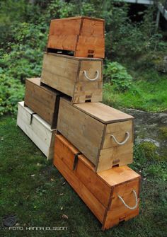 several wooden boxes are stacked on top of each other in the grass near some trees