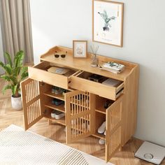 a wooden desk with two open doors on it's sides and a potted plant next to it