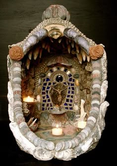 an ornate fountain with candles in it and some decorations on the wall behind it,