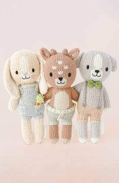 three knitted teddy bears standing next to each other in front of a pink background