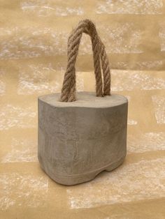 a cement container with rope tied to it on top of a beige floored surface