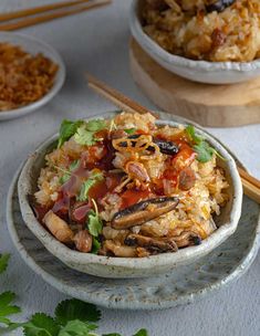 a bowl filled with rice and meat on top of a table next to chopsticks