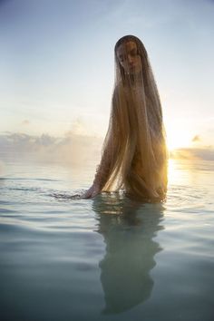 the woman is floating in the water with her long hair flowing over her head and body