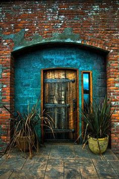 an old brick building with a wooden door and potted plants