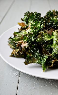 a white plate topped with cooked broccoli on top of a wooden table