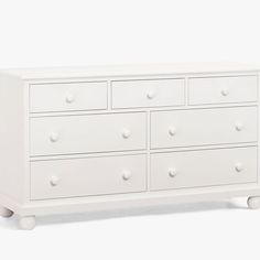 a white dresser with six drawers and four knobs on the bottom drawer, against a white background