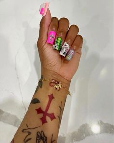 a woman's hand with tattoos and bracelets on her wrist holding up a pink ribbon