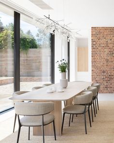 a dining room table with chairs and a potted plant in the center, next to a large window