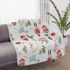 a couch with a christmas themed blanket on it next to a potted plant and window