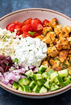 a bowl filled with chicken, cucumber, tomatoes, onions and feta cheese