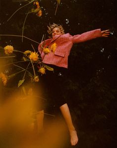 a woman is flying through the air with flowers in her hand