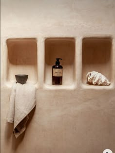 three niches in the wall with towels and soap dispenser on them