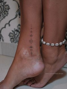 a close up of a person's foot with tattoos on it and an ankle chain