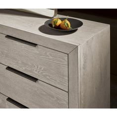 a bowl of fruit sitting on top of a wooden dresser