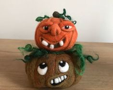 two pumpkins sitting on top of each other with their faces painted orange and green