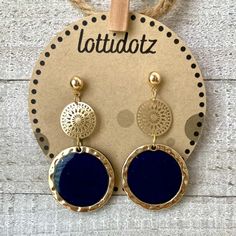 the blue and gold earrings are hanging from a string on a wooden hanger with a tag