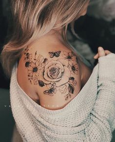 a woman with a flower tattoo on her upper back shoulder and shoulders is looking at the camera