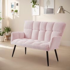 a pink couch sitting on top of a wooden floor next to a potted plant