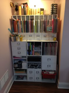 a white shelf filled with lots of files and folders next to a wall mounted light