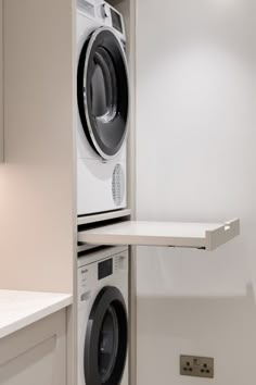 a washer and dryer in a small room with white cupboards on the wall