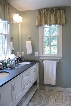 a bathroom with two sinks and towels hanging on the rack in front of the window