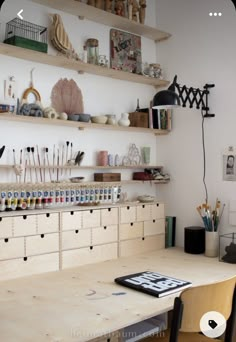 a wooden table topped with lots of crafting supplies next to shelves filled with items