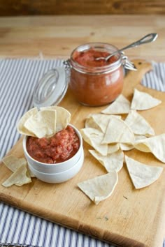 a wooden cutting board topped with chips and salsa