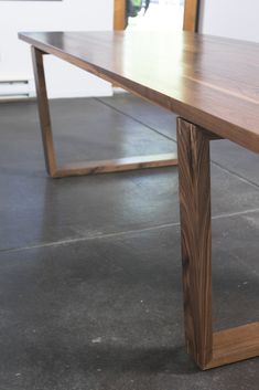 a wooden table sitting on top of a cement floor next to a wall and window