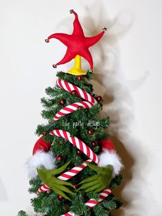 a christmas tree decorated with red and white candy canes, green frog's hands and a star on top