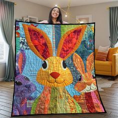 a woman holding up a colorful quilt with rabbits on it