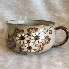 a white and brown coffee cup with flowers on the inside is sitting on a table