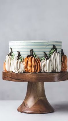 a cake decorated with pumpkins on top of a wooden platter and striped icing