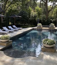 a swimming pool with lounge chairs and umbrellas in the middle, surrounded by trees