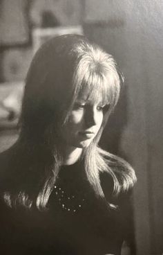 an old black and white photo of a woman with long blonde hair looking at her cell phone