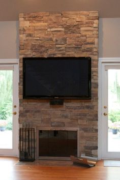 a flat screen tv mounted to the side of a stone fireplace