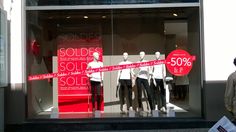 a store window with mannequins in front of it and sale signs behind them