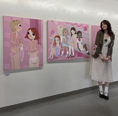 a woman standing in front of three cartoon paintings