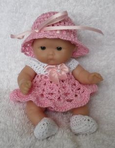 a baby doll wearing a pink crocheted dress and hat