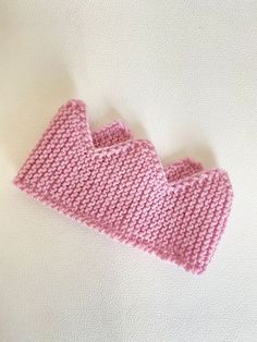 a pink knitted object laying on top of a white surface